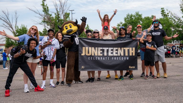 CU Boulder students gather around a banner to celebrate Juneteenth