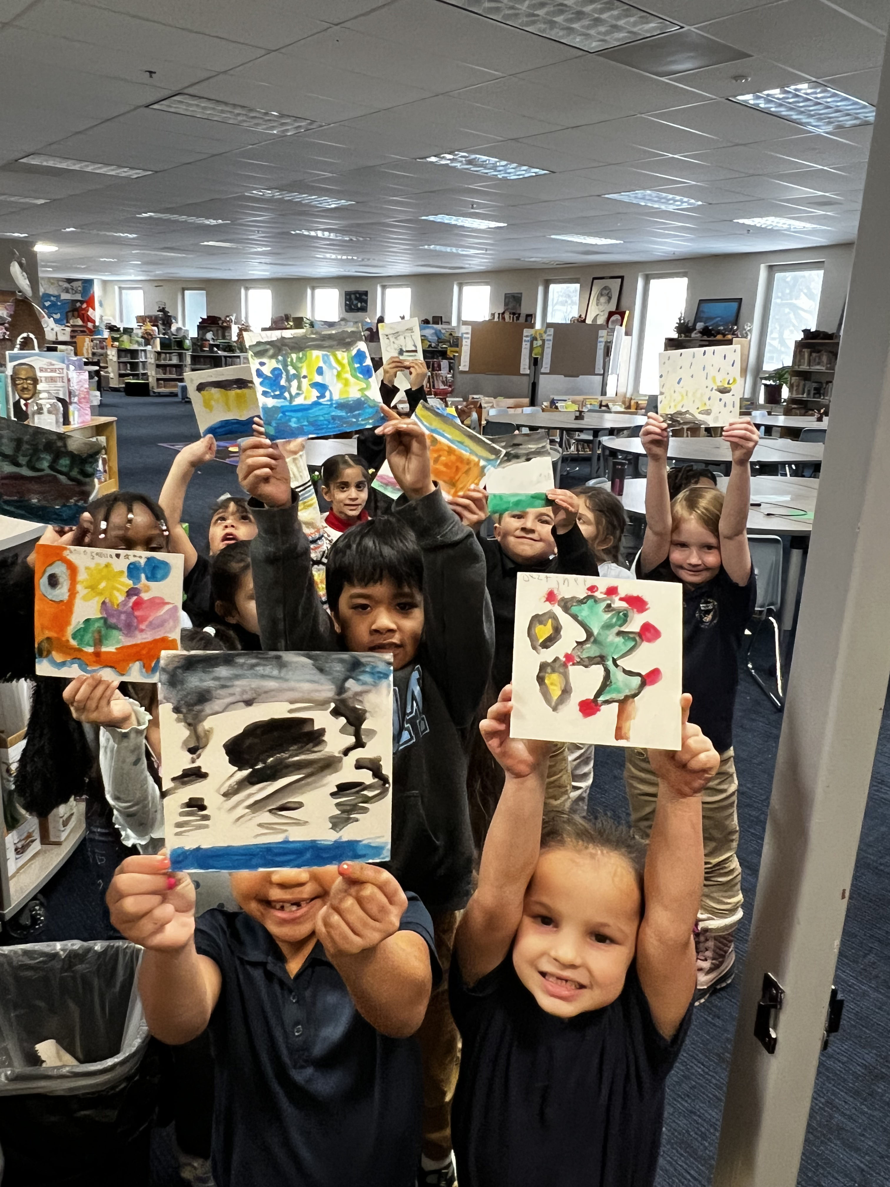 Kindergarteners from Denver's Maxwell Elementary School show off their artwork after participating in a lesson about the water cycle with CU Boulder’s Elementary Arts Lab. The process of making the watercolor paintings was used to illustrate the water cycle in real time (precipitation from their brush to the paper and then evaporation of water from the paper leaving the painting behind).